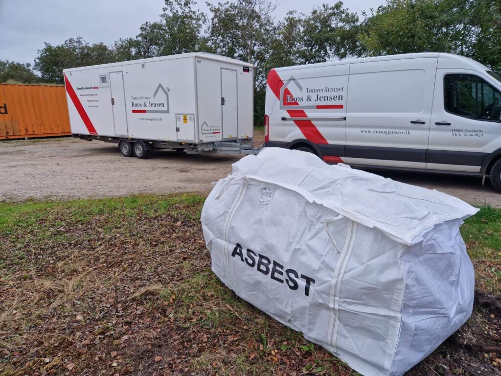 Asbestaffaldsæk og tømrerbil på byggeplads.